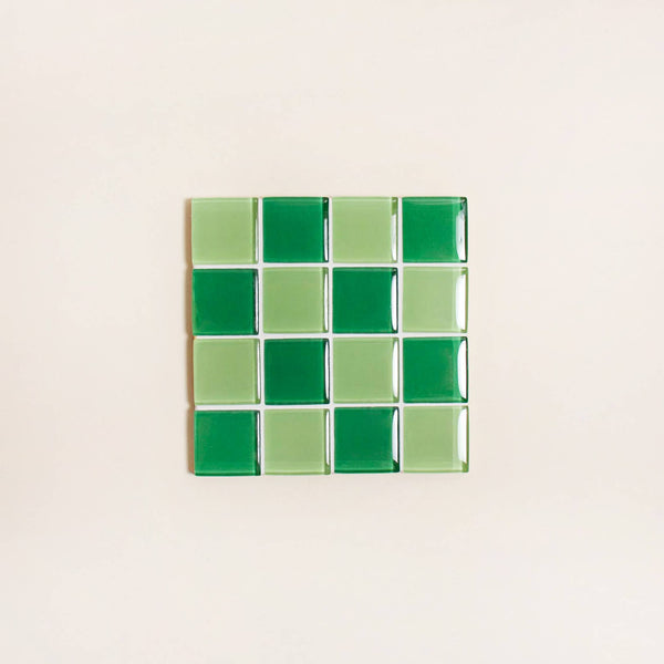 Square tile with green and light green checkered pattern on a beige background