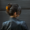 Person with a honey colored hair clip in their bun against a dark background