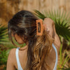 Woman with long hair wearing an orange clip outdoors