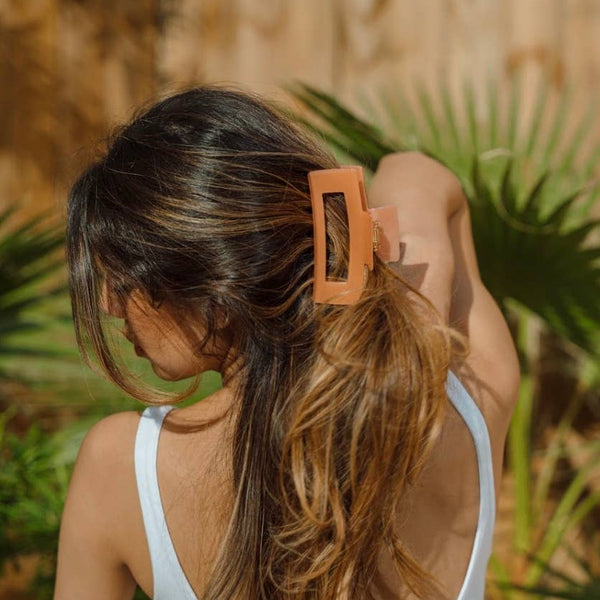 Woman with long hair wearing an orange clip outdoors