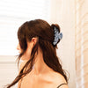 Woman with long dark hair wearing a blue hair claw in front of a window with blinds.