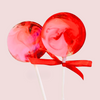 Two red and pink lollipops tied with a red ribbon on a light pink background