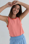 Woman wearing a red and white striped tank top and blue pants against a plain background