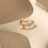 Pair of gold hoop earrings on a beige surface with soft shadows