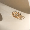 Gold chain ring on a beige surface with soft shadows