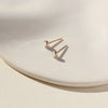 Gold opal stud earrings on neutral background.