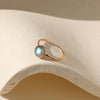 Gold ring with labradorite stone on neutral background.