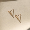 Gold arc stud earrings on a neutral background.