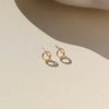 Gold mini circular stud earrings on a neutral background.