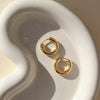 Gold hoop earrings on a white ceramic dish
