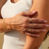 Close-up of a person's hand with gold jewelry on a neutral background