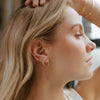 Close-up of a woman wearing gold hoop earrings with a blurred background