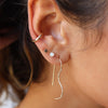 Close-up of an ear wearing gold hoop earrings with a blurred background