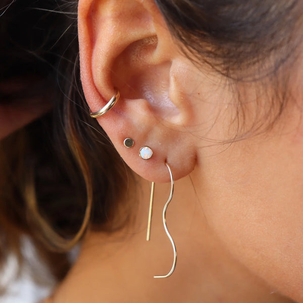 Close-up of an ear wearing gold hoop earrings with a blurred background