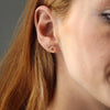 Close-up of person wearing a stack of gold stud earrings.