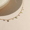 Gold necklace with small colored beads on a beige background