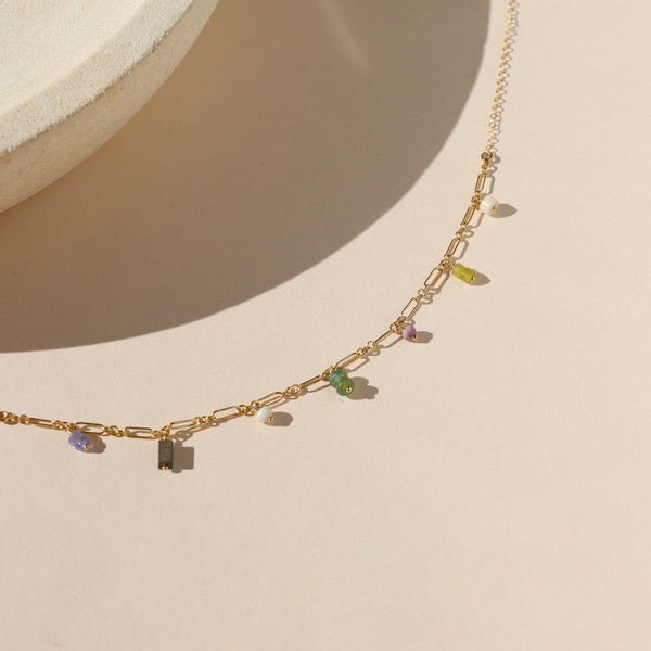 Gold necklace with small colored beads on a beige background