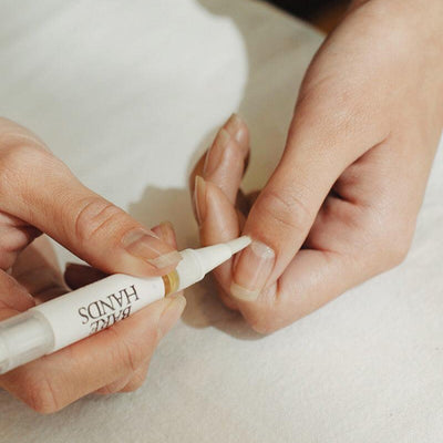 Person applying a product to their nails with a small applicator