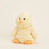 Plush yellow baby chick stuffed animal on beige background.
