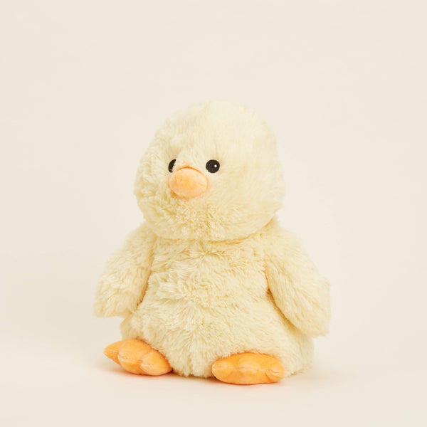 Plush yellow baby chick stuffed animal on beige background.