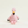 Pink plush flamingo toy on a light beige background