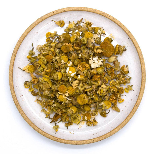 Chamomile loose leaf tea on a white plate.