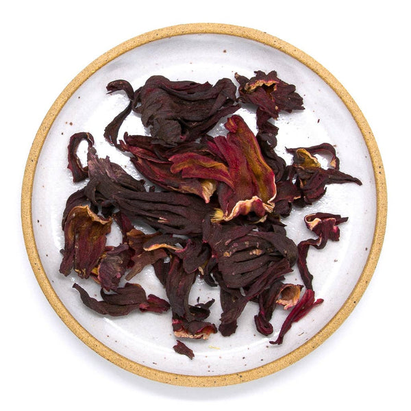 Dried hibiscus flowers on a white plate with a gold rim