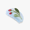 Blue hair comb with strawberry and leaf design on a white background