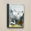 An illustrated children's book called 'You Belong Here' featuring a greyscale illustration of a town with a white rabbit in the foreground. The book sits against a neutral backdrop.