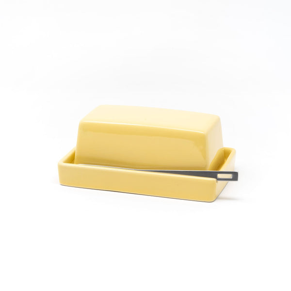 Yellow butter dish with a knife on a white background