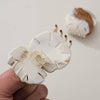 White hair clip held by a hand with a blurred background