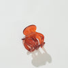 A translucent amber-orange mini claw hair clip on a clean white background with a soft shadow.