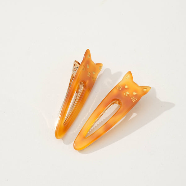 Two orange tortoiseshell cat-shaped hair barrette clips on a white background