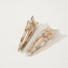Pair of cat shaped taupe tortoiseshell hair clips with gold accents on a light beige background