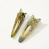 Two green cat-shaped hair clips on a white background