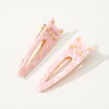 Two pink cat-shaped hair clips with gold accents on a white background