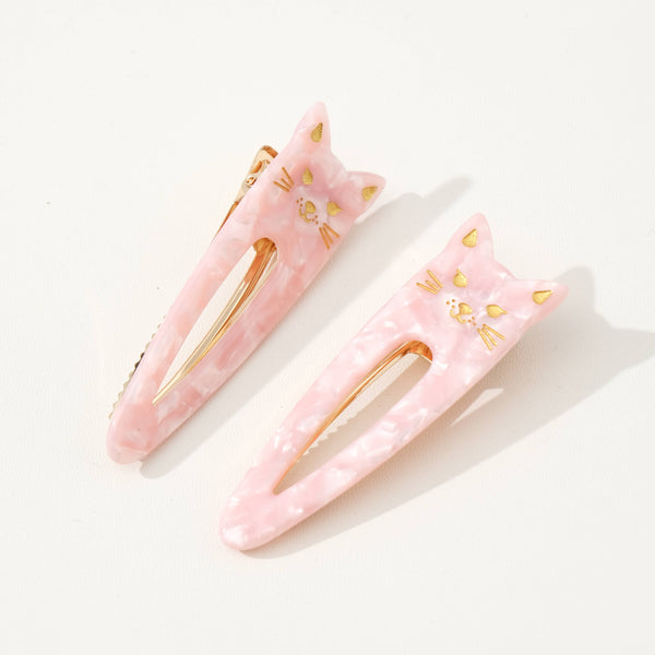 Two pink cat-shaped hair clips with gold accents on a white background