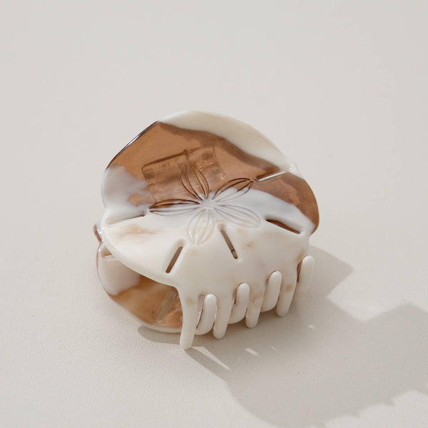 White and bronze sand dollar hair clip on a light gray background