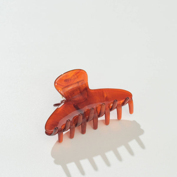 A translucent amber-brown hair claw clip on a clean white background with a soft shadow.