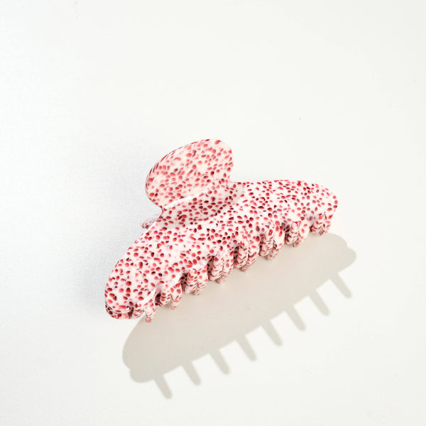A large claw-style hair clip with a glossy white base covered in small red speckles, photographed on a clean white background with a soft shadow.