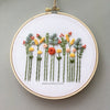 Embroidery hoop with floral design on a plain grey-green background