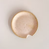 Glazed matte pink orange ceramic spoon rest on neutral background.