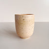 Speckled pink-orange ceramic cup on a light gray background