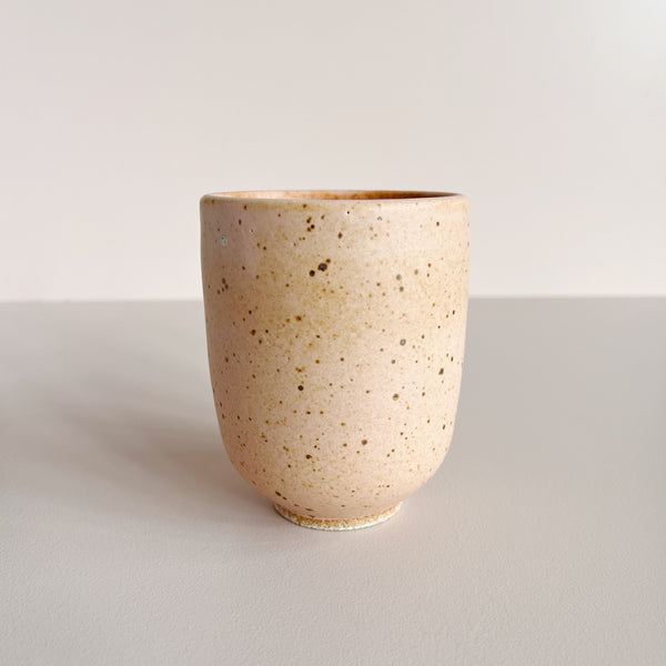 Speckled pink-orange ceramic cup on a light gray background