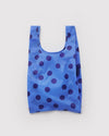 A small nylon shopping back in blue with navy polka dots on a white backdrop.