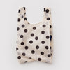 A small reusable nylon shopping bag in cream and black polka dots against a white backdrop.