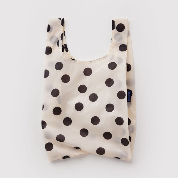A small reusable nylon shopping bag in cream and black polka dots against a white backdrop.
