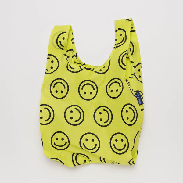 A small nylon shopping bag in bright yellow with black smiley faces against a white backdrop.