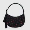 A black nylon half moon crossbody bag with a dainty red and green wildflower print on a white background.
