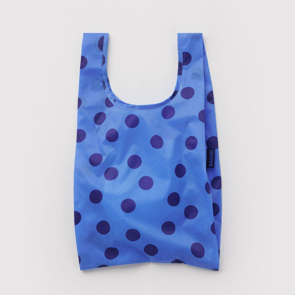 Blue reusable tote bag with purple polka dots on a light gray background